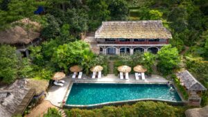 Vue aérienne par drone d'un hôtel avec piscine entouré de végétation tropicale